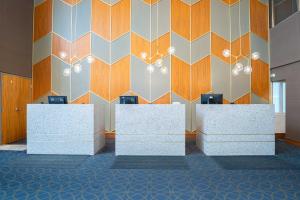 a lobby with white reception desks and a geometric wall at Sandman Signature Mississauga Hotel in Mississauga