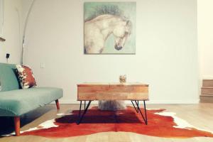 a living room with a table and a horse painting on the wall at All-ways Home in Burnaby