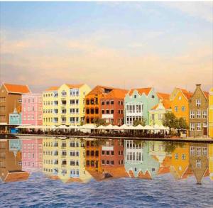 un grupo de edificios coloridos que reflejan en el agua en City Views Spacious Mezzanine Apartments, en Willemstad