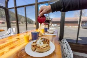 a person pouring a glass of wine over a plate of food at RiverWalk Inn in Pagosa Springs