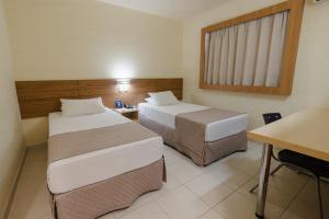 マリンガにあるHotel Caiuá Expressのベッド2台とデスクが備わるホテルルームです。