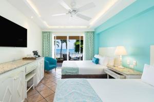 タマリンドにあるHotel Tamarindo Diria Beach Resortのベッド2台、薄型テレビが備わるホテルルームです。