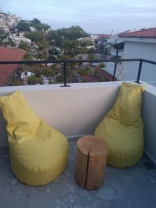 two yellow bean bag chairs and a stump on a balcony at Grecos STAY SKIATHOS in Skiathos Town