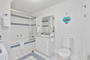 a white bathroom with a toilet and a sink at Rooftop Island Sunsets in Bongaree +26 photos
