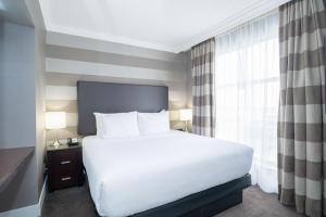 Un dormitorio con una gran cama blanca y una ventana en Sandman Signature Mississauga Hotel, en Mississauga