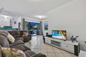 a living room with a couch and a flat screen tv at Rooftop Island Sunsets in Bongaree
