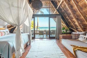 a bedroom with a bed and a view of the ocean at Ahau Beachfront Tulum Hotel in Tulum