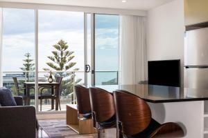 a living room with a table and chairs and a large window at Coast on Colley Luxury 1BR Glenelg in Glenelg