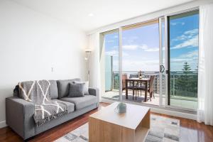 a living room with a couch and a table at Coast on Colley Luxury 1BR Glenelg in Glenelg