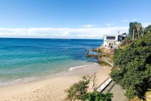 a house on a hill next to the ocean at Watch The Sunrise Over Coogee 2 Bedrooms+Garage in Sydney