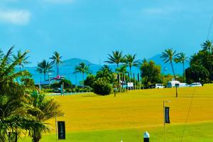 a golf course with palm trees and a green field at Absolute Luxury Marina Lifestyle at The Port of Airlie Beach in Airlie Beach
