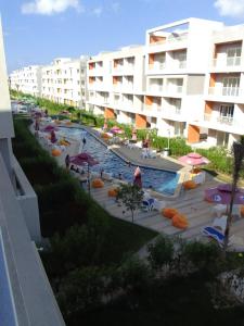 una piscina con sillas y sombrillas junto a un edificio en شاليه سياحي بمارينا دلتا لاجونز المنصورة الجديدة en Al Ḩammād