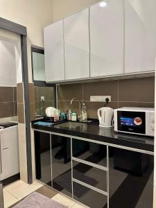 a kitchen with white cabinets and a counter with a microwave at Cozy 2 BR Apartment w/ Pool Gym Wi-Fi & Work Space in Klang