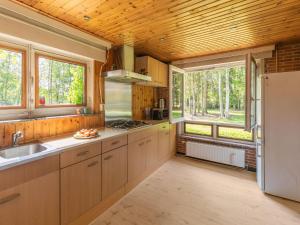 una cocina con techos de madera, armarios y ventanas de madera en Lovely chalet in Arendonk with terrace en Arendonk