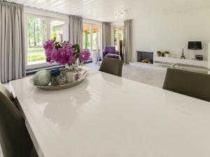 una mesa de comedor blanca con flores púrpuras. en Lovely chalet in Arendonk with terrace en Arendonk