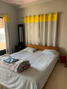 a bedroom with a large white bed with yellow curtains at Spacious Penthouse in heart of city. By GEC circle in Chittagong