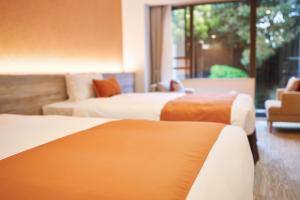 a hotel room with three beds and a couch at WeBase KAMAKURA in Kamakura
