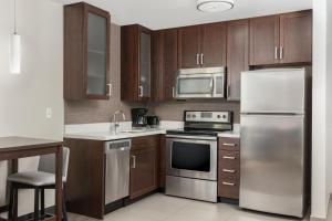 a kitchen with stainless steel appliances and wooden cabinets at Residence Inn by Marriott Kansas City at The Legends in Kansas City