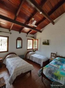 1 dormitorio con 2 camas y techo de madera en Quinta El Descanso en General Alvarado