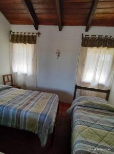 a bedroom with two beds and two windows at Quinta El Descanso in General Alvarado
