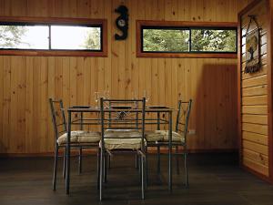 a dining room with a table with chairs and two windows at Casa Vacacional Panguipulli in Panguipulli