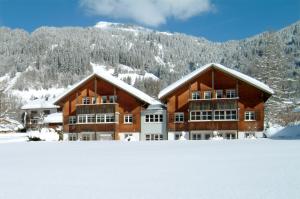 ein großes Gebäude im Schnee vor einem Berg in der Unterkunft Ferienwohnungen Erath in Schoppernau