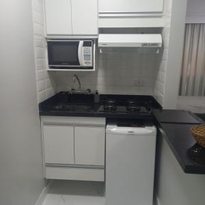 eine kleine Küche mit einer Spüle und einer Mikrowelle in der Unterkunft Paulista Flat in São Paulo