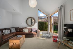 a living room with a couch and a large window at Wanaka Tranquility - Wanaka Holiday Home in Wanaka