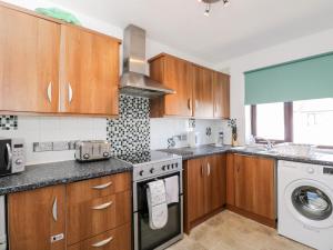 a kitchen with wooden cabinets and a washer and dryer at Sea Breeze in Burnham on Sea