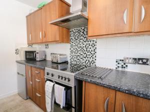 a kitchen with wooden cabinets and a stove top oven at Sea Breeze in Burnham on Sea