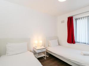 2 camas en una habitación con cortina roja en Sea Breeze, en Burnham-on-Sea