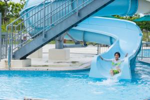 un niño deslizándose por un tobogán de agua en una piscina en Southern Beach Hotel & Resort en Itoman