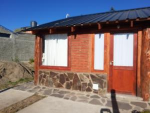 Cabañas El Colibrí في تريفيلين: مبنى من الطوب مع نافذتين وباب
