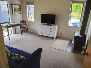 a living room with a tv on a dresser with a tvicterictericter at Akatarawa Valley and River Retreat a Cosy Two Bedroom Guest Suite in Upper Hutt
