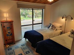 two beds in a room with a window at Akatarawa Valley Retreat a Cosy Two Bedroom Guest Suite in Upper Hutt
