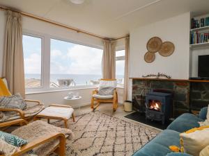 uma sala de estar com lareira e vista para o oceano em Wootton Gray em Mousehole