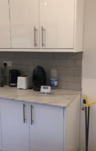 eine Küchentheke mit weißen Schränken und einem Toaster in der Unterkunft Falcon drive Room 2 in Oldham