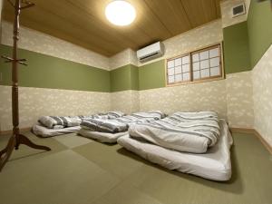 uma fila de colchões alinhados num quarto em WuTong梧桐 通天閣徒歩1分 NEW OPEN 景区内民宿 em Osaka