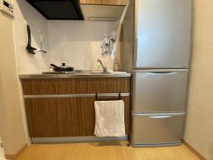 uma cozinha com um frigorífico de aço inoxidável e um lavatório em WuTong梧桐 通天閣徒歩1分 NEW OPEN 景区内民宿 em Osaka