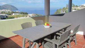 una mesa con sillas y un bol de fruta en el balcón en B&B Il Cappero, en Lipari