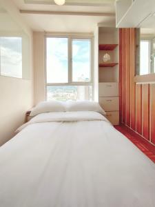 - un lit blanc dans une chambre avec 2 fenêtres dans l'établissement Topaz 1 Bedroom Suite Orochi Staycation PH at Centrio Towers, à Cagayán de Oro