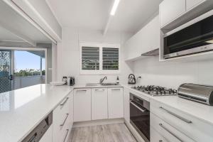 a white kitchen with a sink and a stove at Castaway in Laurieton