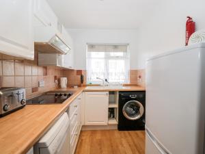 a kitchen with white cabinets and a refrigerator at Ocean Breeze in Burnham on Sea