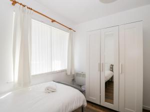 バーナム・オン・シーにあるOcean Breezeの白いベッドルーム(ベッド1台、鏡付)