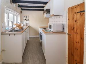 a small kitchen with white cabinets and a microwave at Lena Cottage in Great Driffield