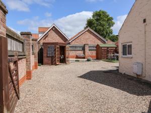 a home with a gravel driveway and brick buildings at Lena Cottage in Great Driffield