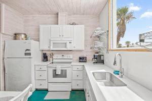 Una cocina blanca con fregadero y refrigerador. en Above & Beyond, en Port Aransas