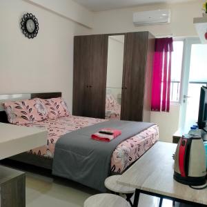 Schlafzimmer mit einem Bett mit rosa Bettwäsche und einem Tisch in der Unterkunft RB Room Bogorienze The Jungle Bogor in Bogor