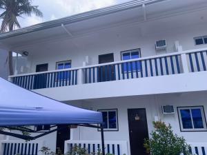 a white building with a balcony and a blue umbrella at Baie Benie Beach Resort in Balibago