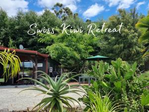 um sinal que lê sol beijar kiwi retiro em um jardim em Swiss-Kiwi Retreat A Self-contained Appartment or a Tiny House option em Tauranga